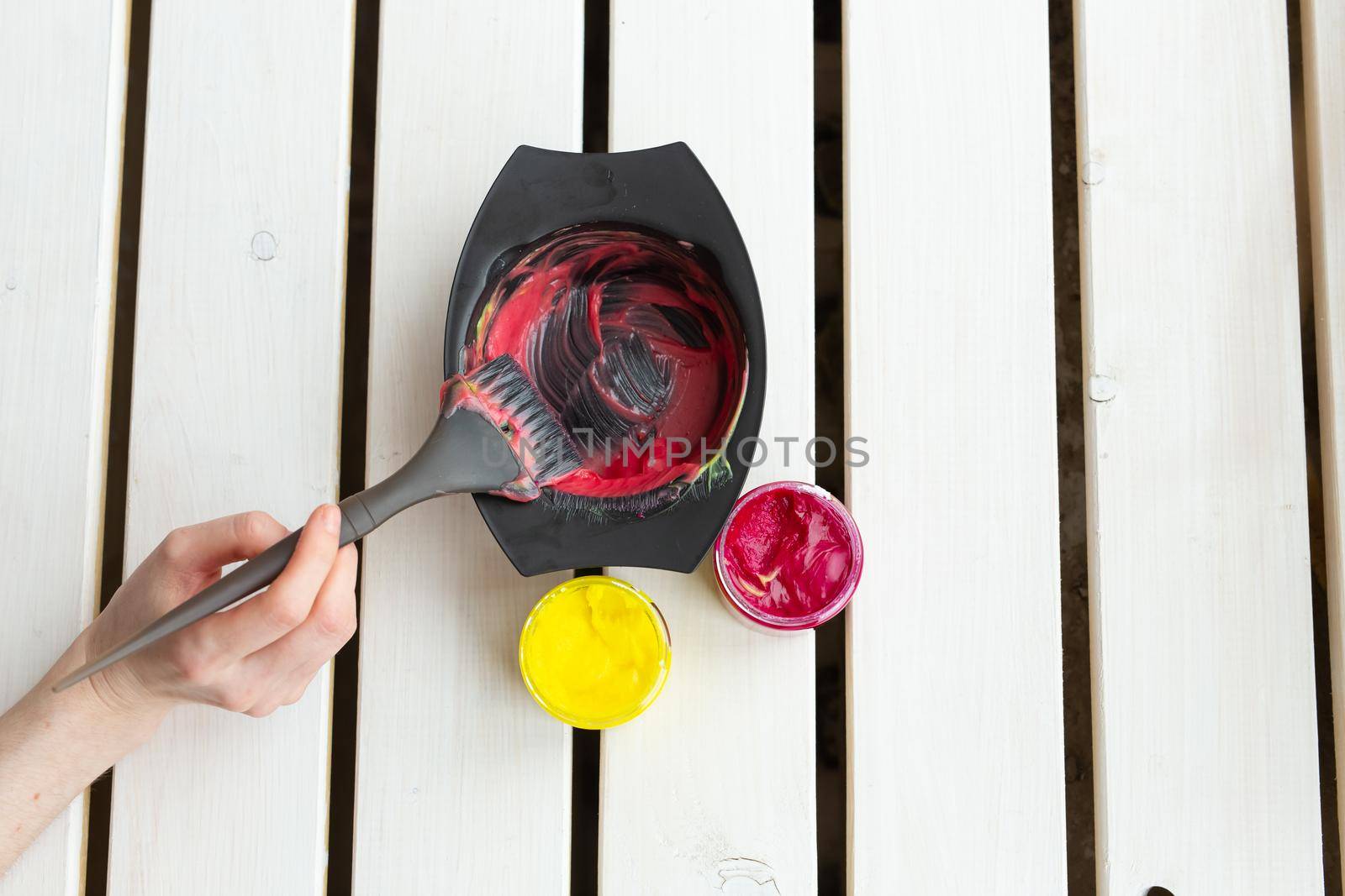 Color and hairdresser concept - female hairdresser in process of mixing hair dye color on the table with white background by Satura86