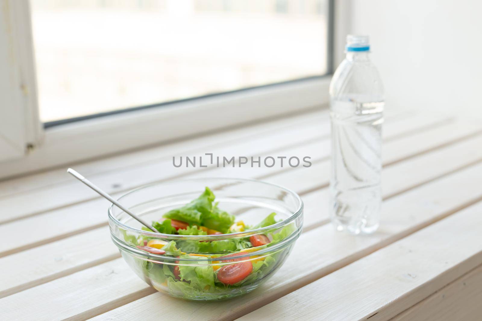 Vegetable salad and bottle of water lie on a white windowsill. Concept of healthy lifestyle physical activity and proper nutrition. by Satura86