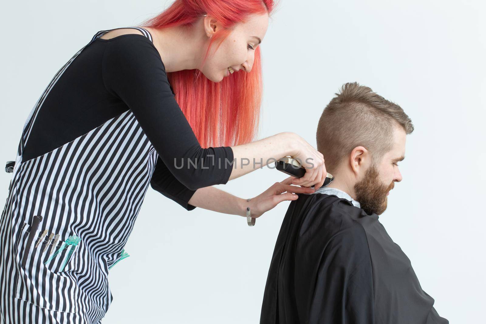 Hairdresser, stylist and barber shop concept - woman hairstylist cutting a man.