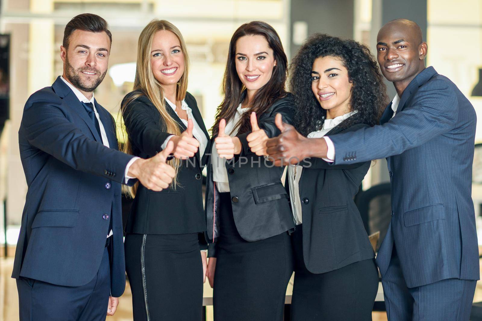 Group of businesspeople with thumbs up gesture in modern office. by javiindy
