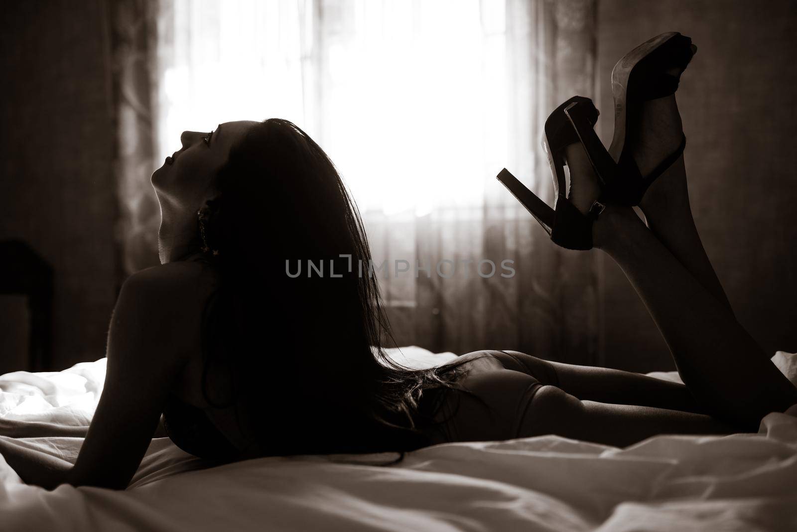 Sexy young woman in lingerie posing on the bed. Soft light and colours