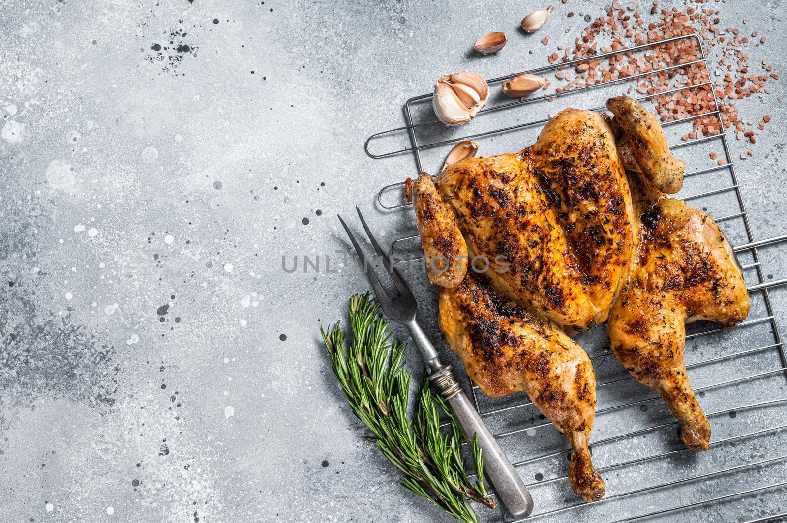 Traditional spatchcocked barbecue chicken on grill. Gray background. Top view. Copy space by Composter