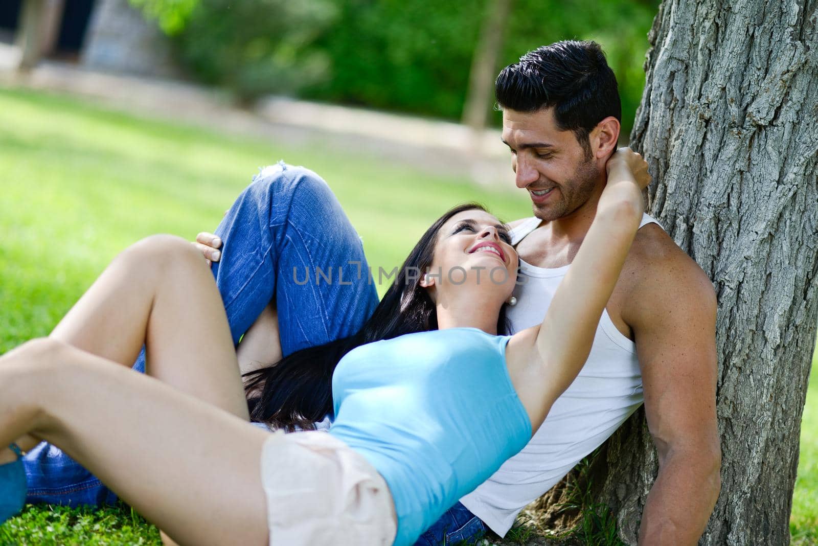 Happy smiling couple laying on green grass by javiindy