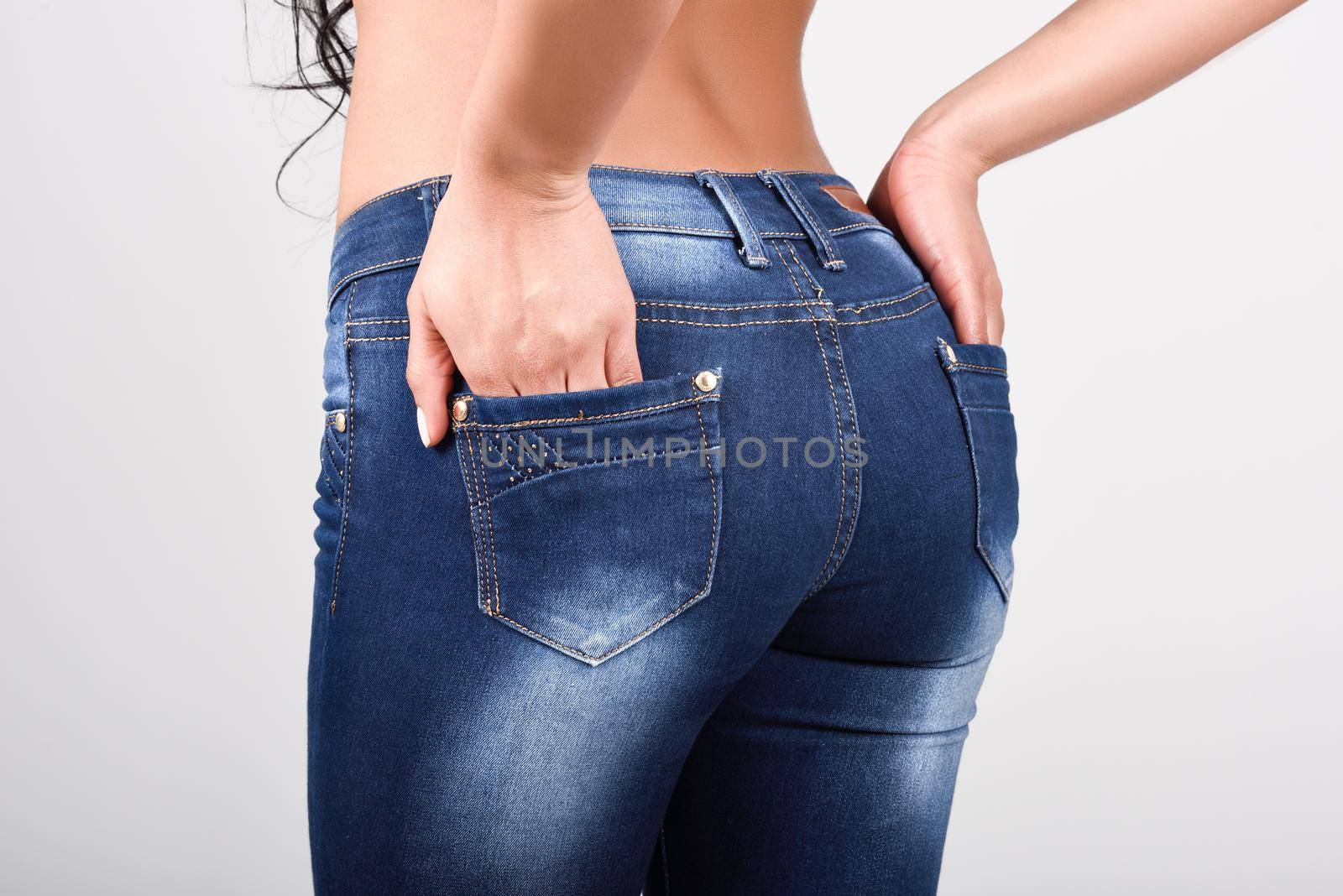 Woman wearing blue jeans with a beautiful waist. Studio shot