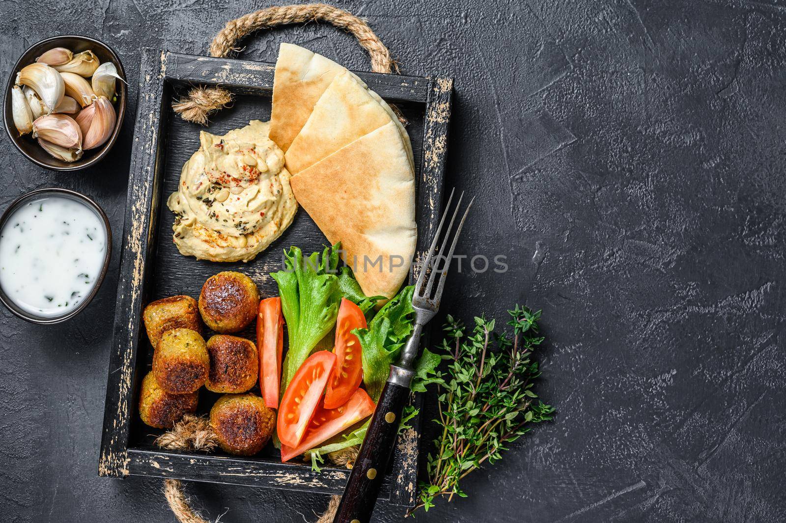 Traditional homemade Hummus chickpea, falafel, pita bread and fresh vegetables. Black background. Top view. Copy space.