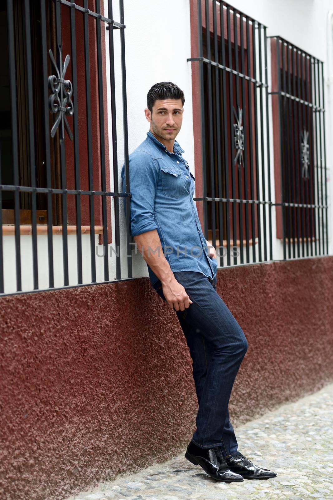 Portrait of a young handsome man, model of fashion, with modern hairstyle in urban background