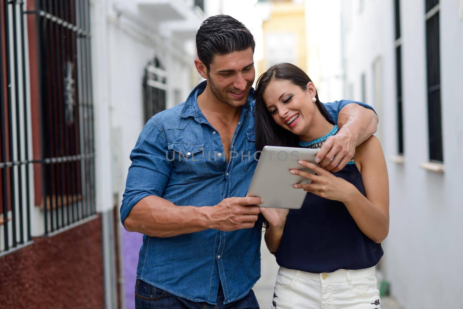 Portrait of beautiful couple with tablet computer in urban background