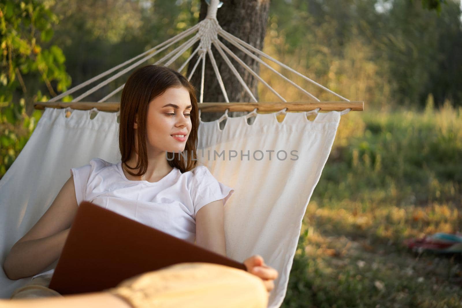 cheerful woman lies in a hammock with a laptop vacation internet travel. High quality photo