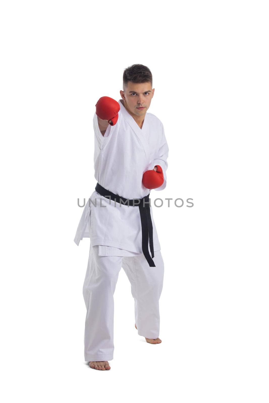Full length portrait of a karate man exercise isolated on white background making a hit