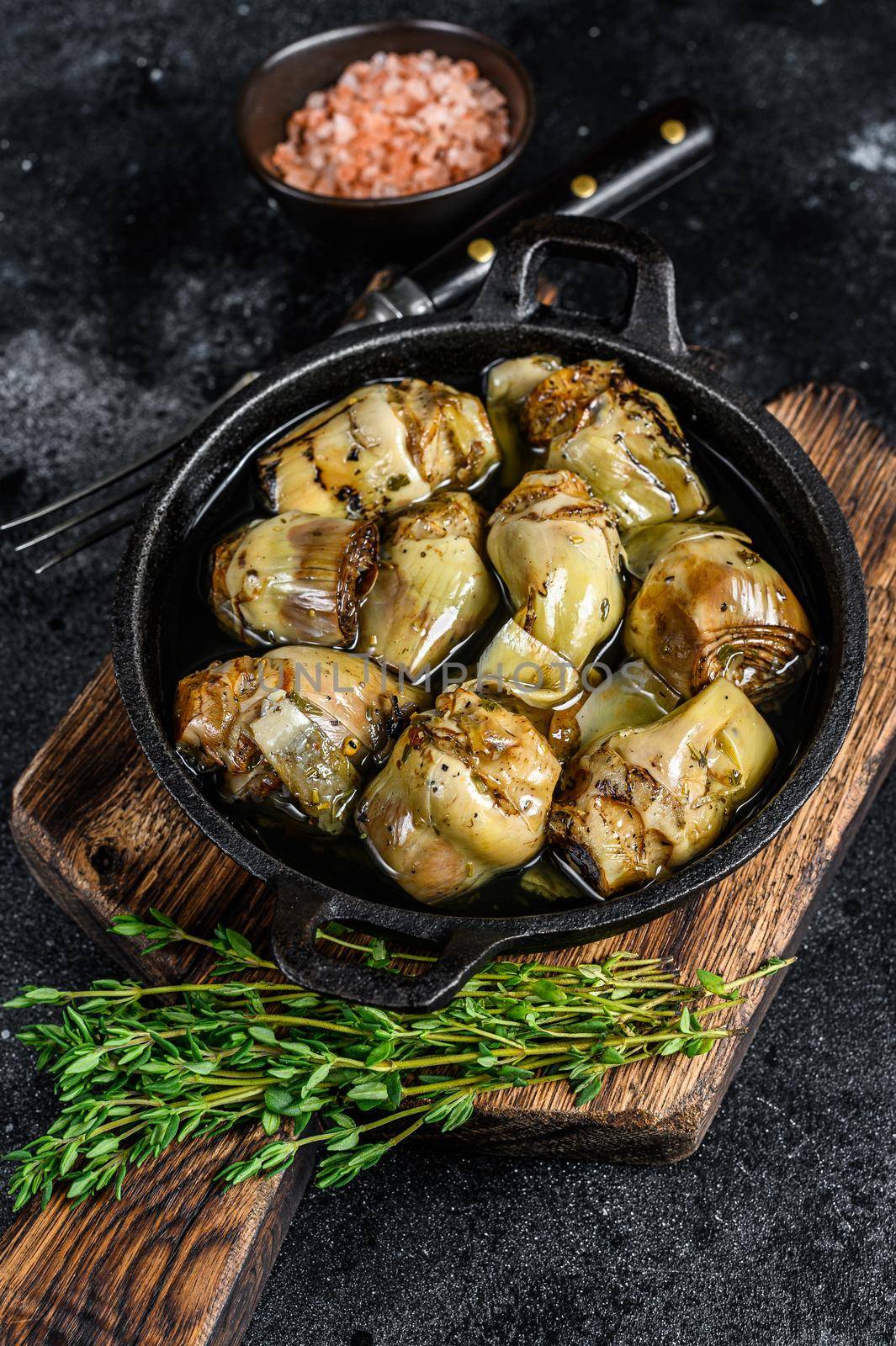 Canned artichokes in olive oil on a rustic wooden kitchen table. Black background. Top view.