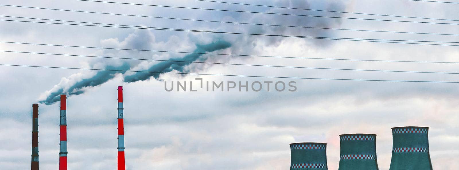 Environmental pollution, environmental problems, smoke from pipes and cooling towers of an industrial enterprise or thermal power plant against the background of a gray cloudy sky.