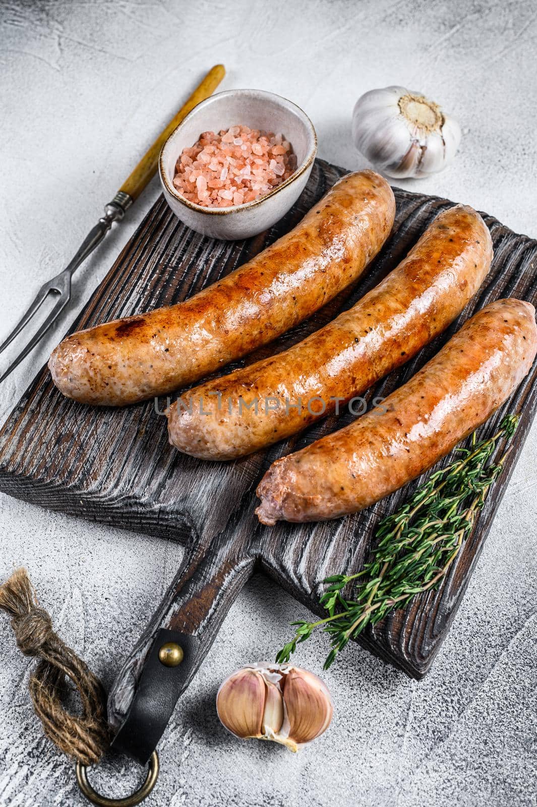 Sausages barbecue fried with spices and herbs on a wooden cutting board. Top view. White background by Composter