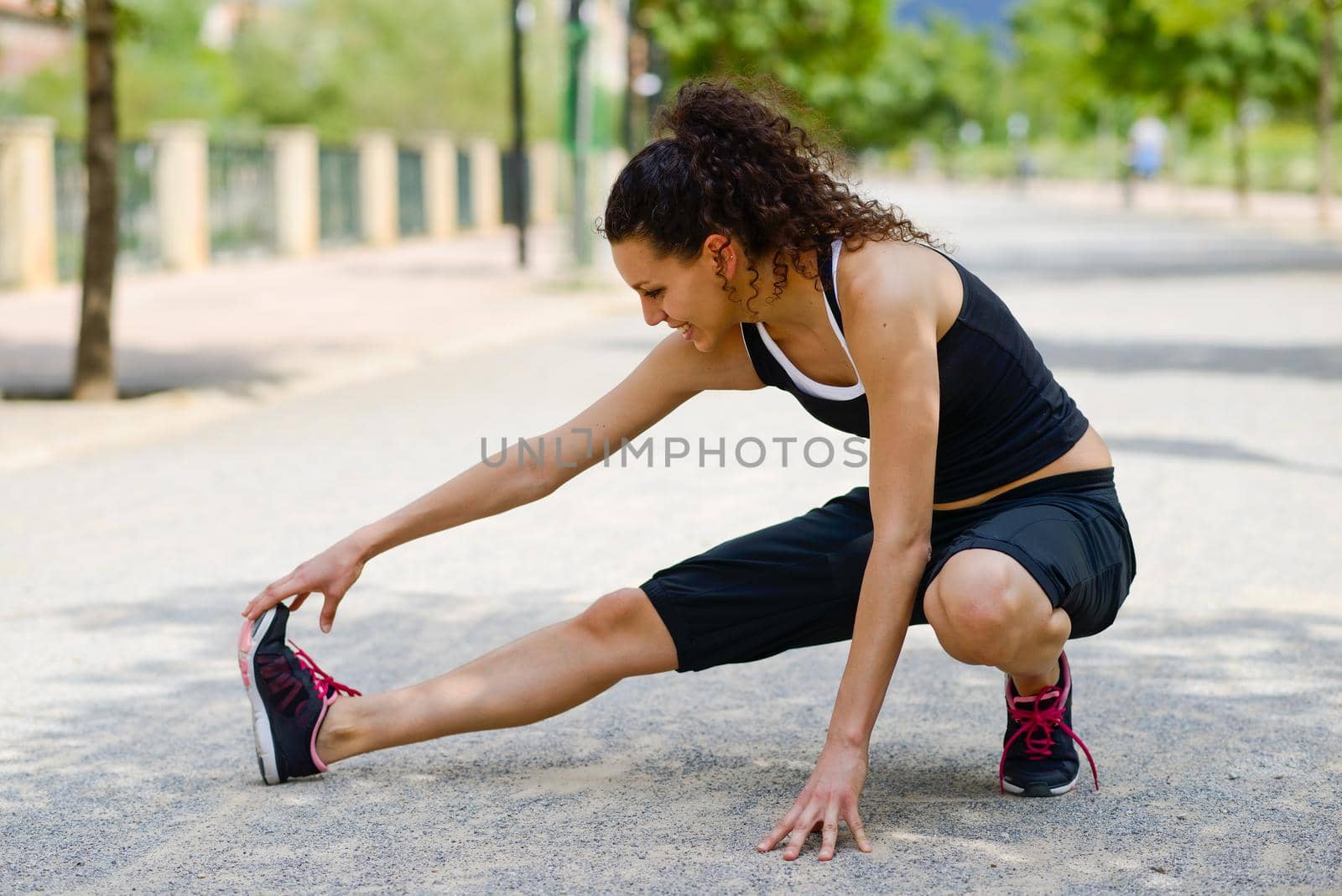 Portrait of young cheerful smiling woman in sports wear in urban background