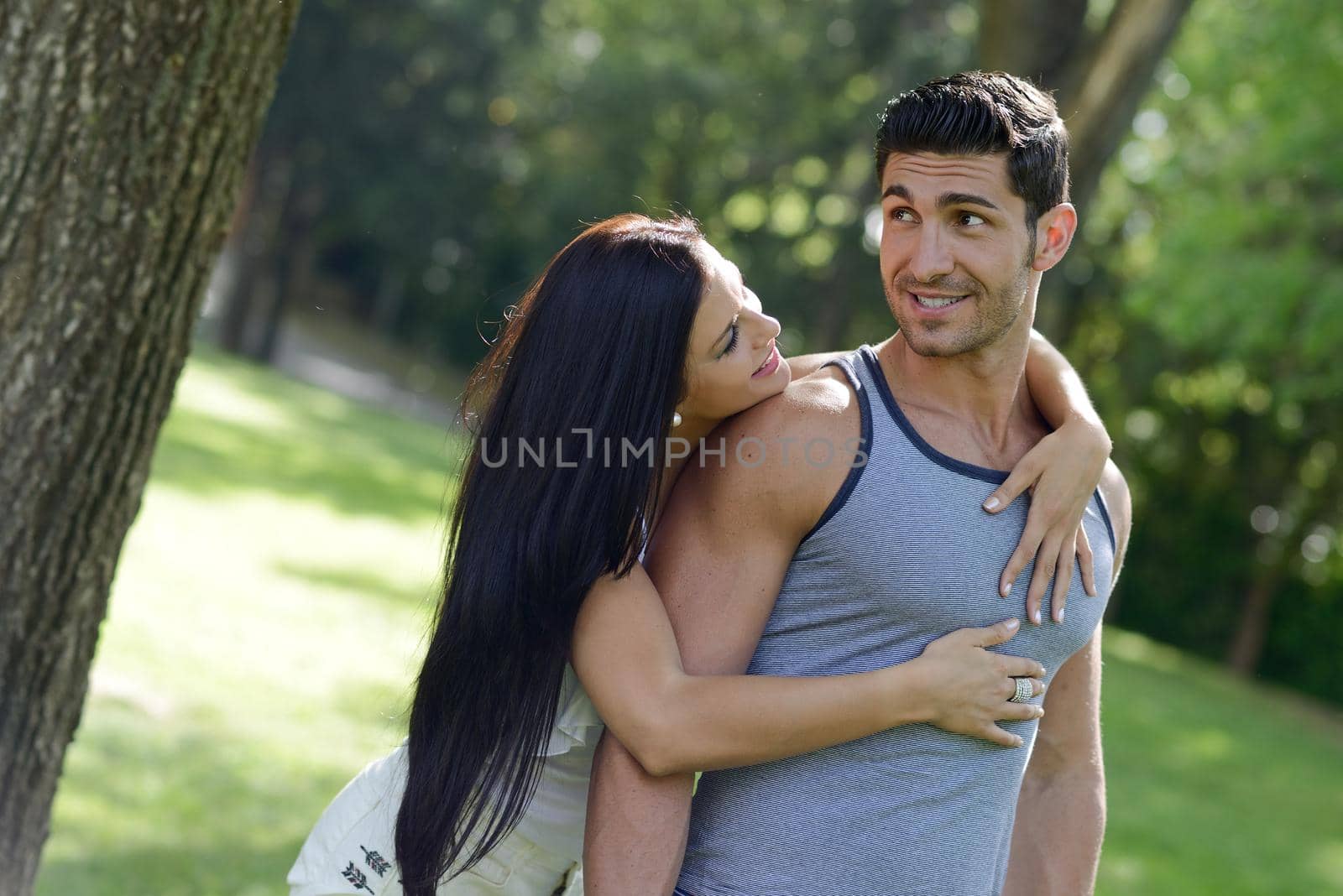 Happy smiling couple laying on green grass in a beautiful park