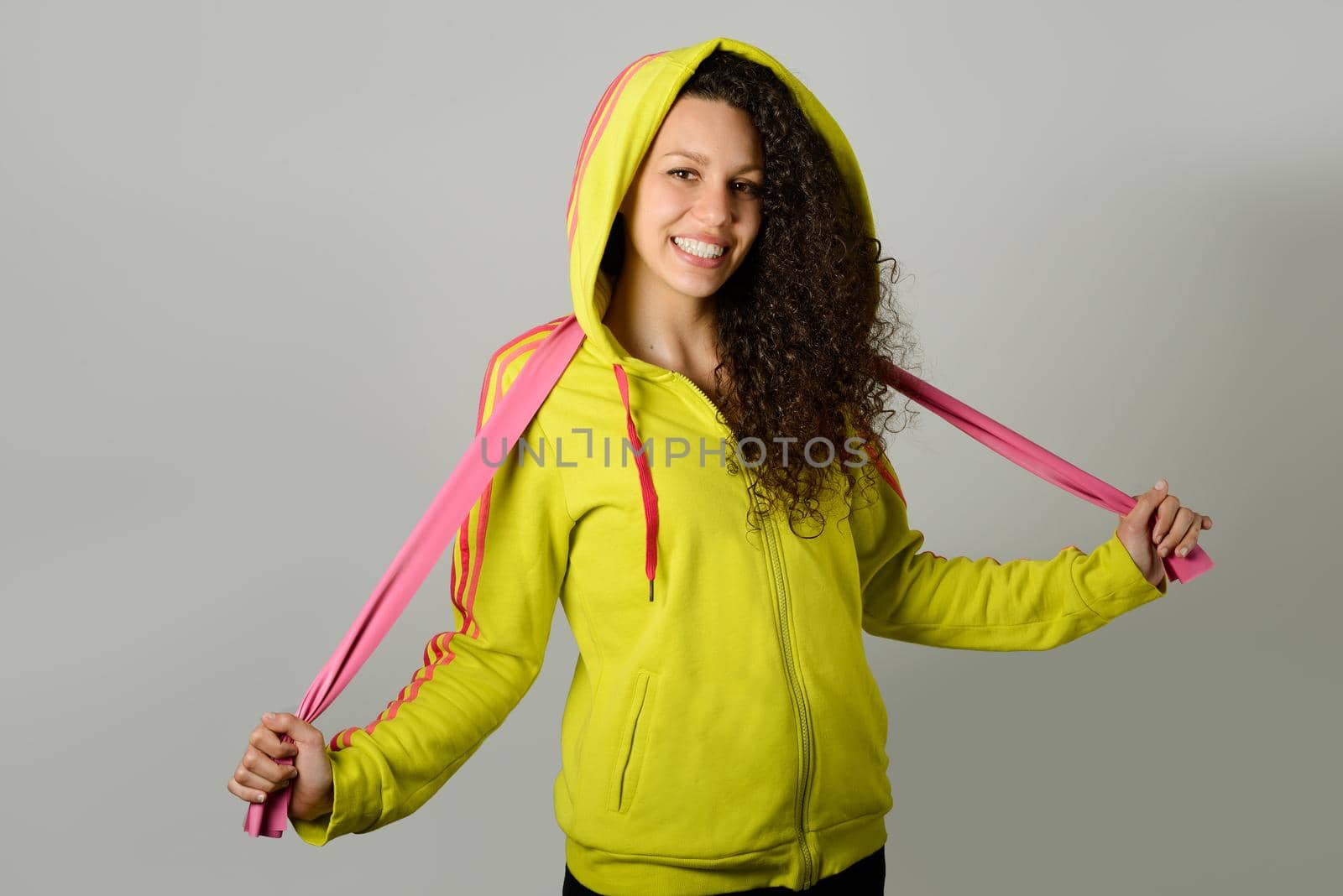 Portrait of young cheerful smiling woman in sports wear on urban background