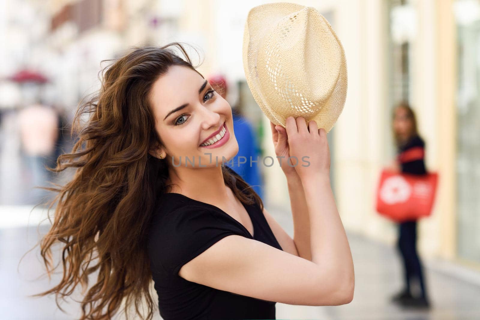 Happy young woman with blue eyes smiling in urban background. Girl wearing summer clothes and sun hat.