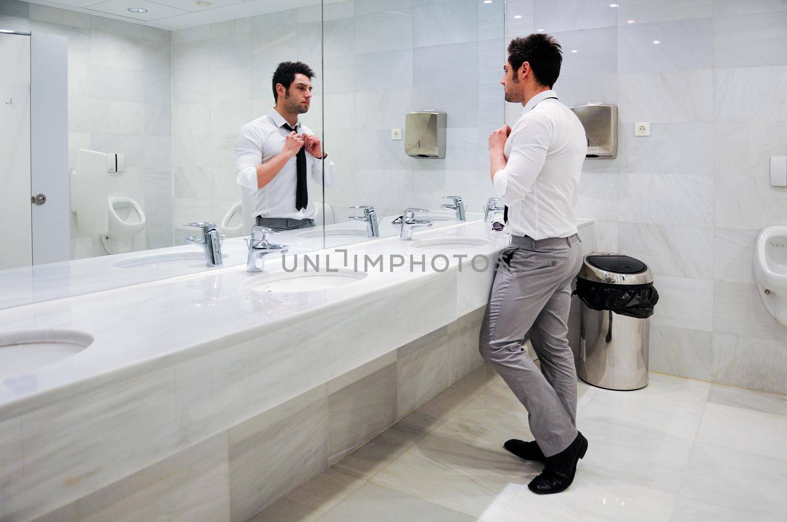 Man getting dressed in a public restroom with mirror