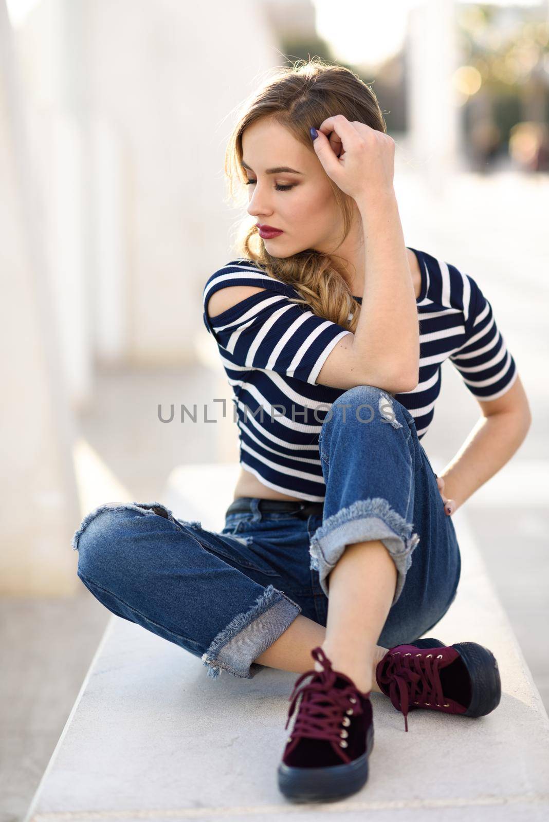 Blonde woman, model of fashion, sitting in urban background. by javiindy