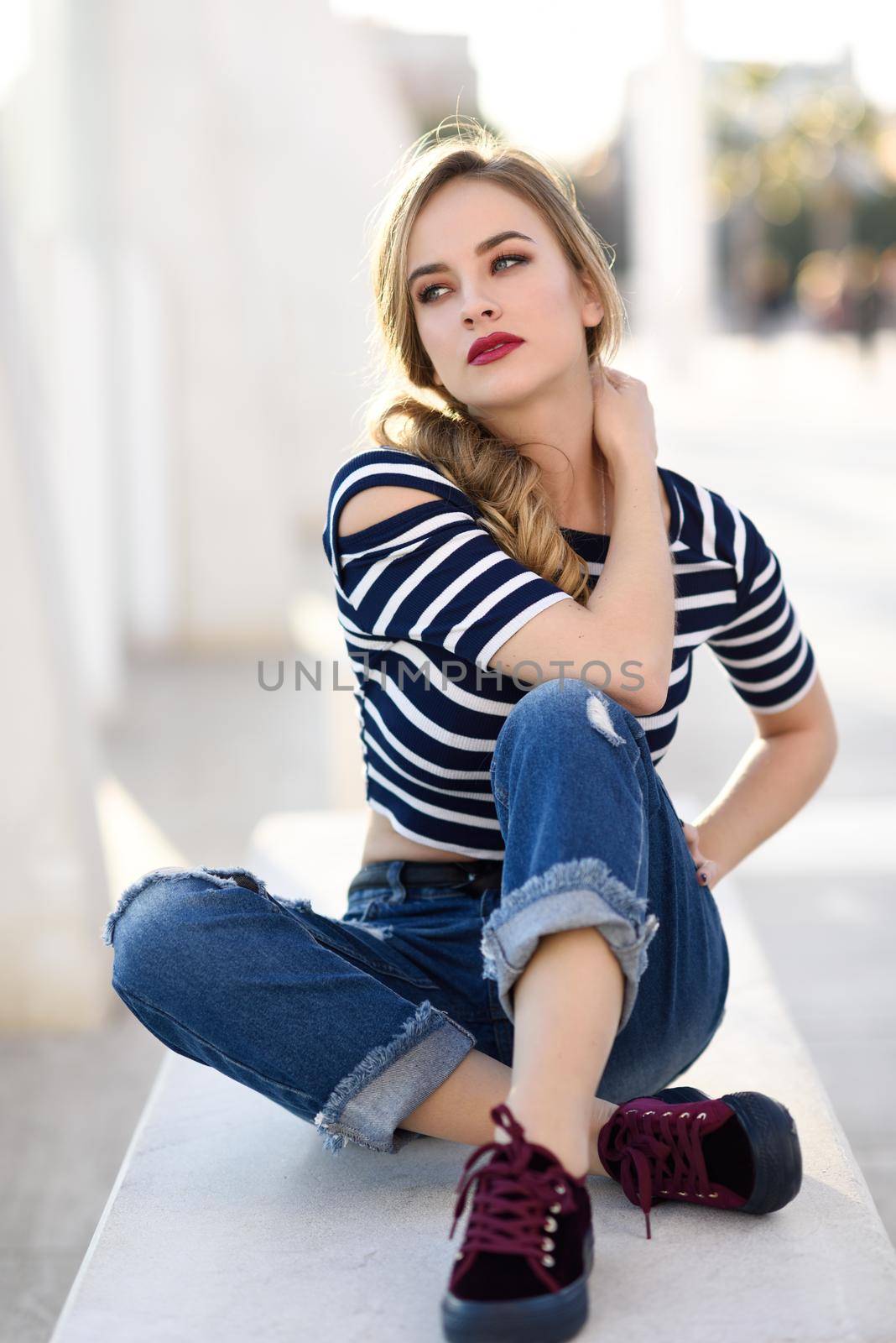 Blonde woman, model of fashion, sitting in urban background. by javiindy