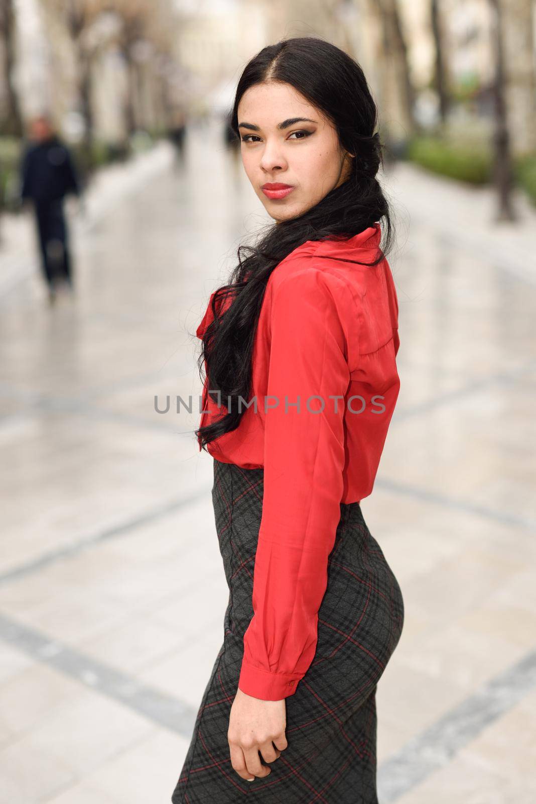 Portrait of hispanic businesswoman in urban background wearing red shirt and skirt