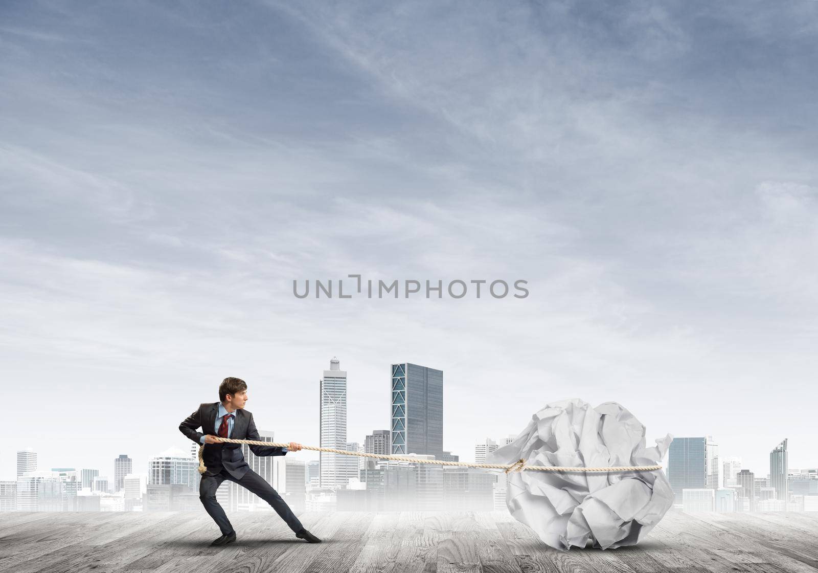 Young businessman outdoors making huge paper ball move