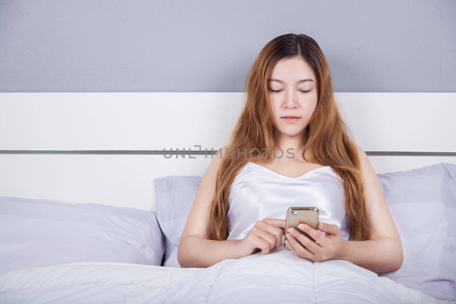 woman using her smartphone on bed by geargodz