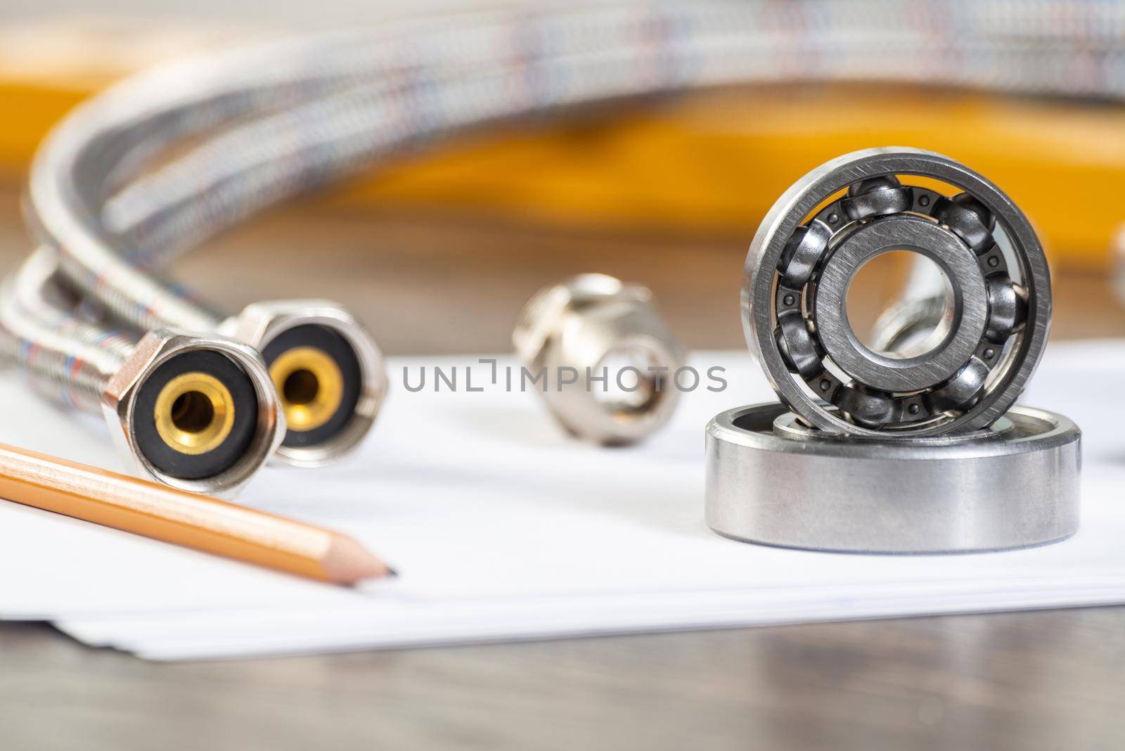 Plumbing pipeline and ball bearings laying on table. Water fittings and connections with segments of braided hose. Steel details for engine mechanisms. House infrastructure designing and installation