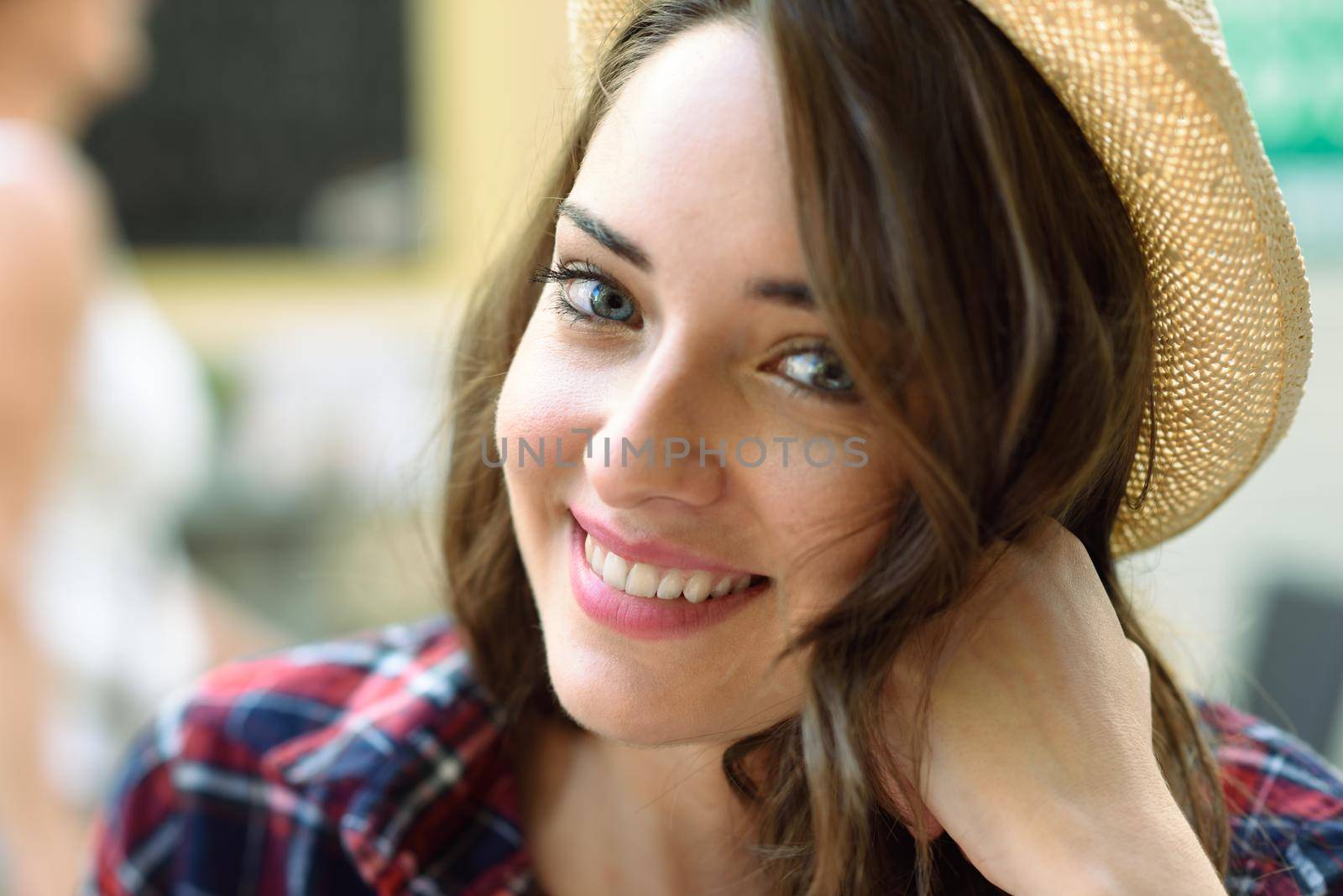 Close-up portrait of young woman with beautiful blue eyes wearing plaid shirt and sun hat