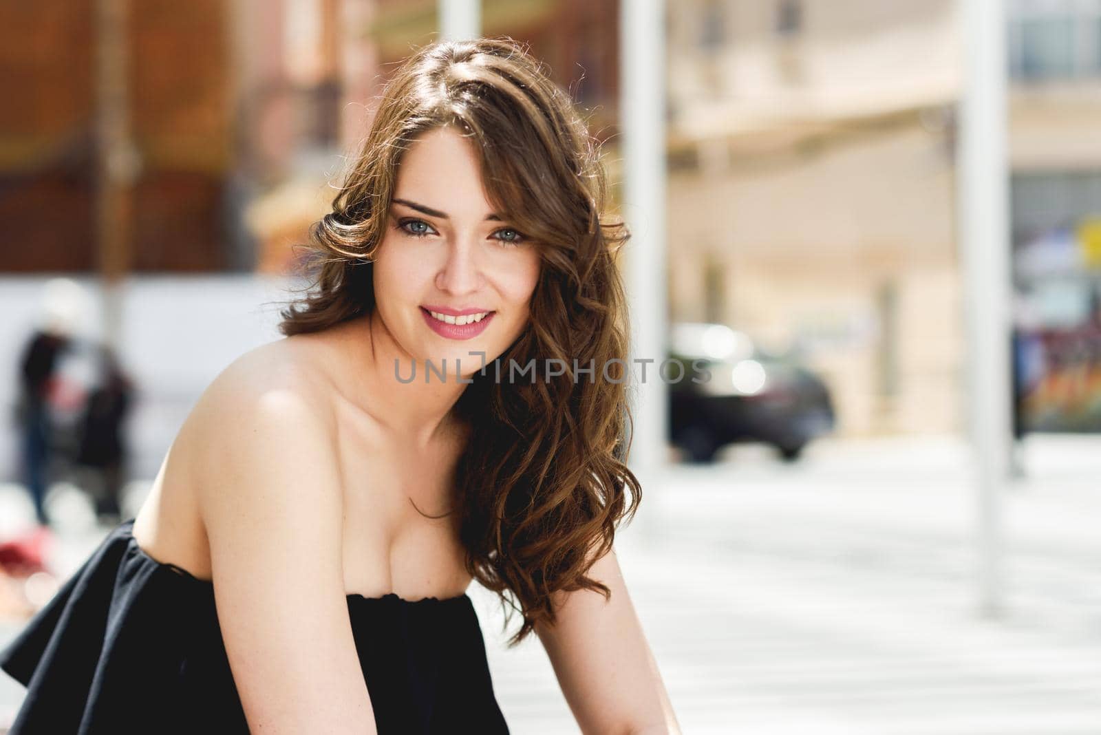 Beautiful young woman with blue eyes smiling in urban background. Girl wearing summer clothes
