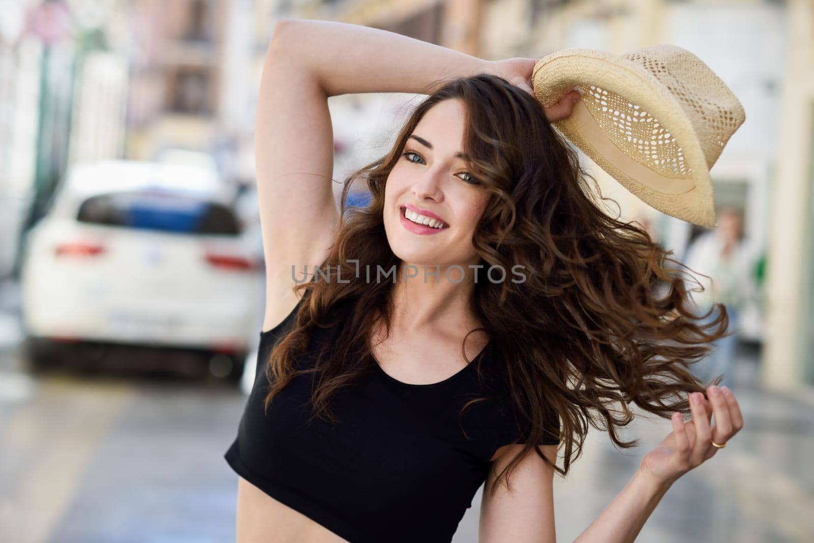 Happy young woman with blue eyes smiling in urban background. Girl wearing summer clothes and sun hat.