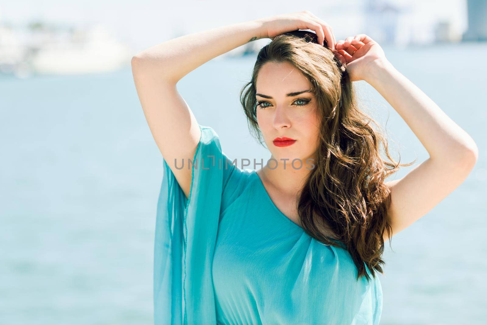Beautiful young woman with blue eyes wearing blue dress in the beach.