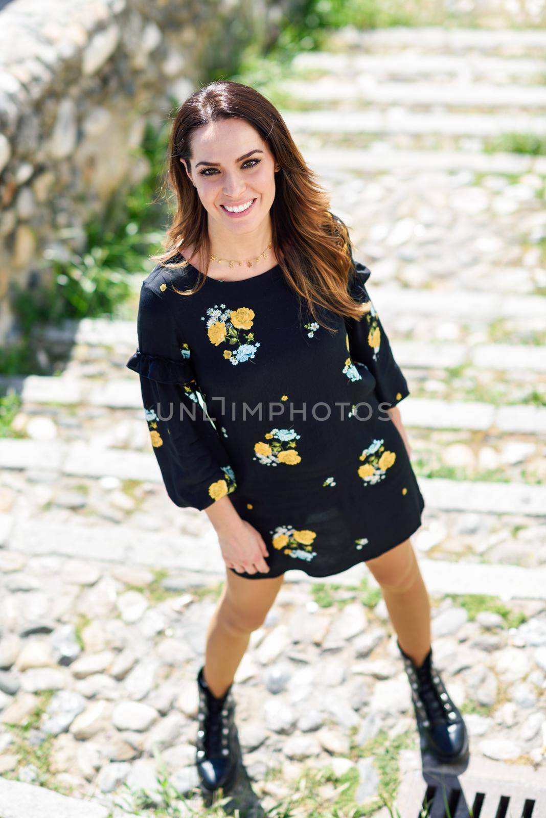 Middle-aged woman, model of fashion, wearing flowered dress in an old neighborhood of Granada in summer