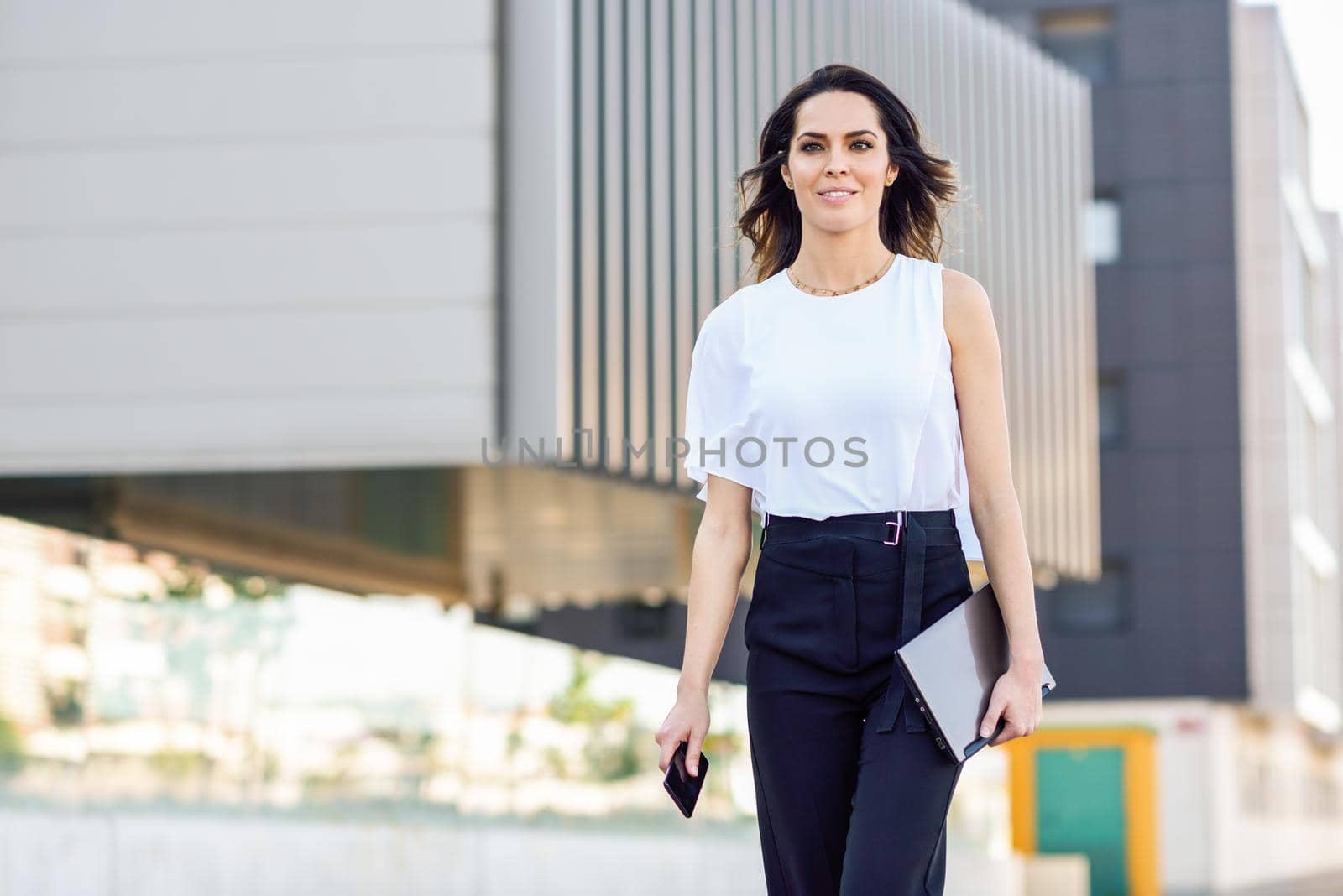 Businesswoman working with her smart phone and laptop outdoors. by javiindy