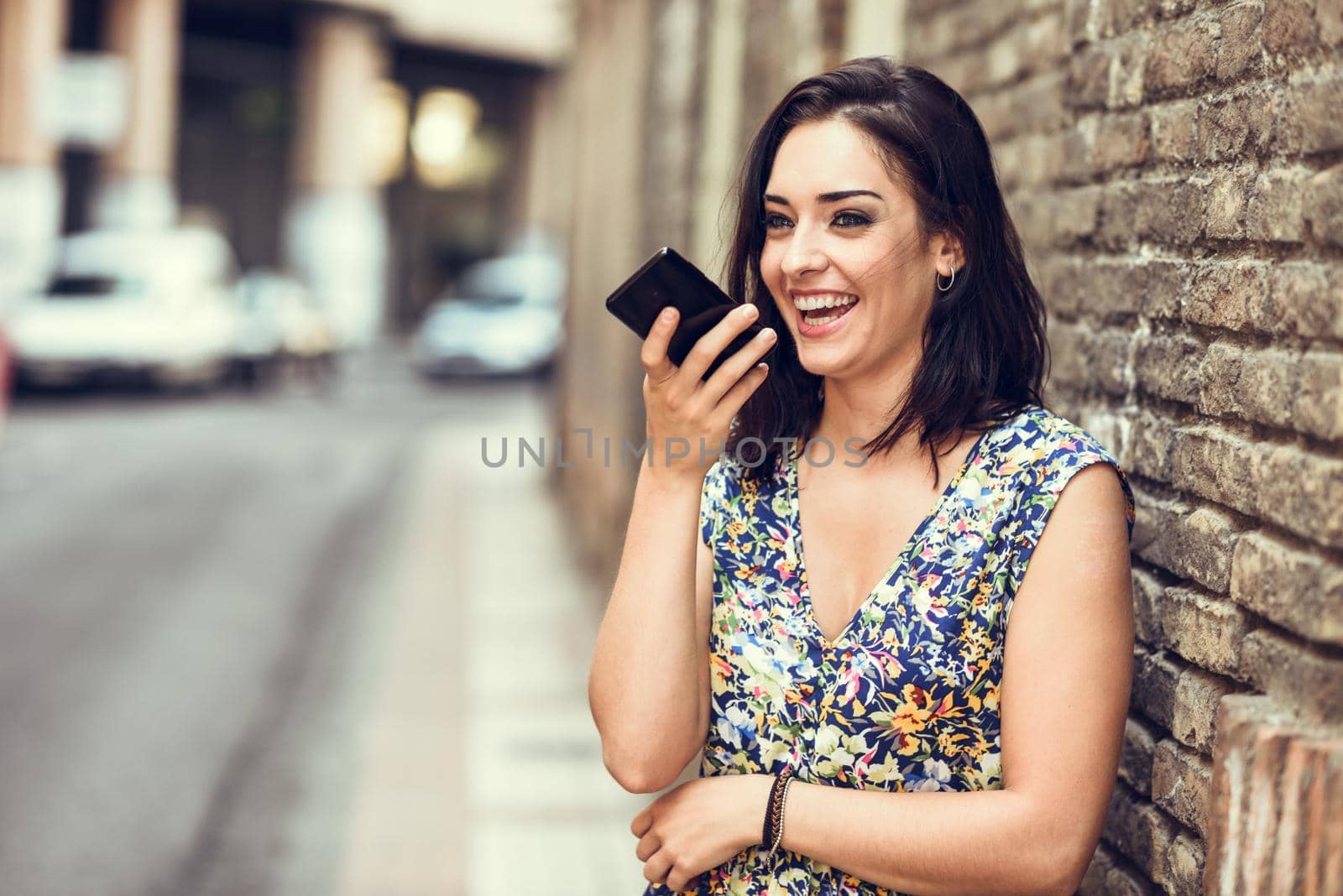 Smiling young woman recording voice note in her smart phone by javiindy