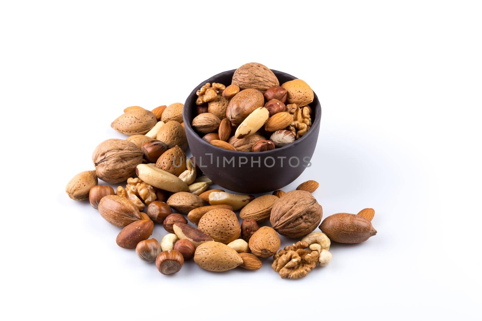 Large diversity of healthy nuts in a dark stone bowl - isolated