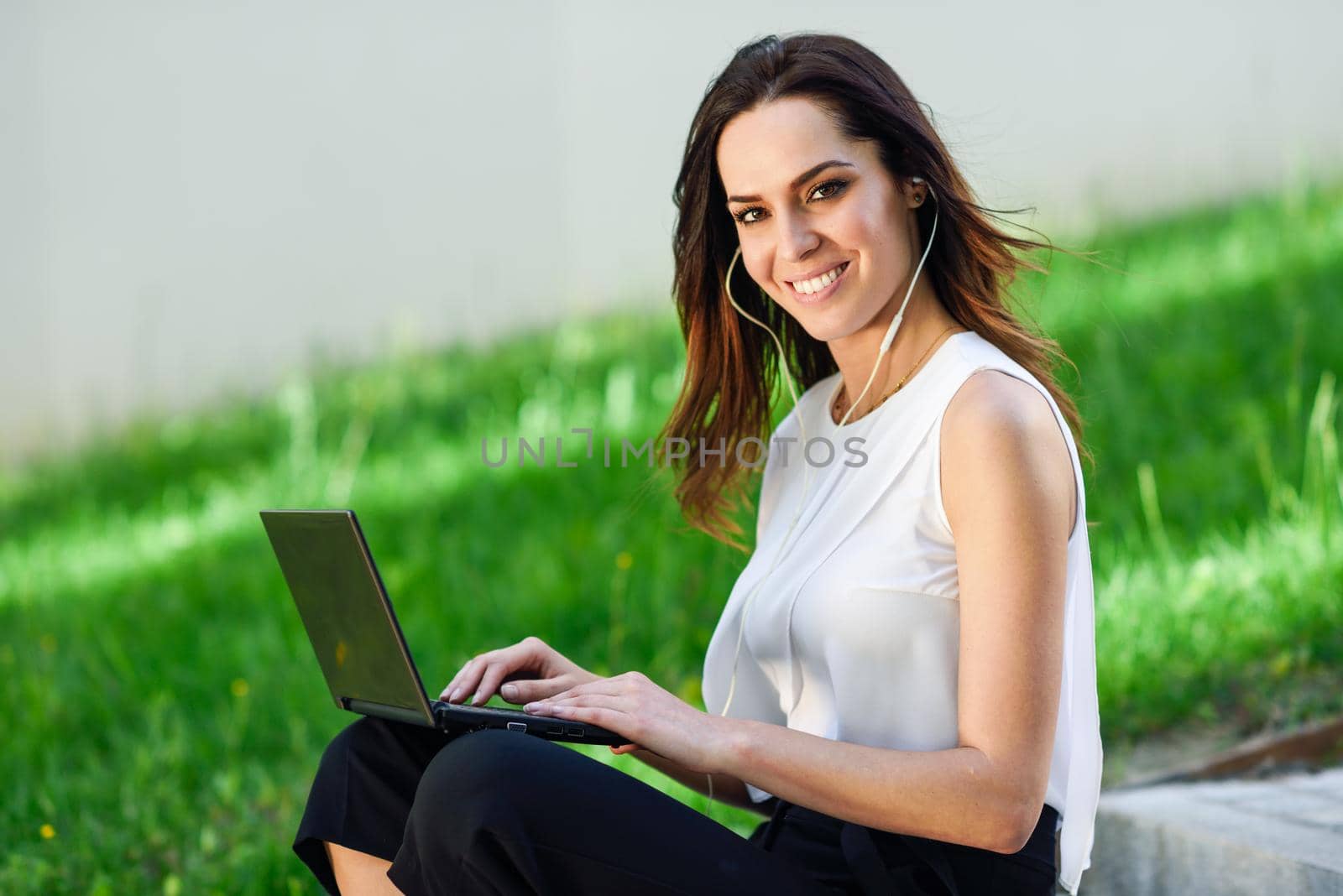 businesswoman working with her laptop computer sitting on urban steps outdoors.