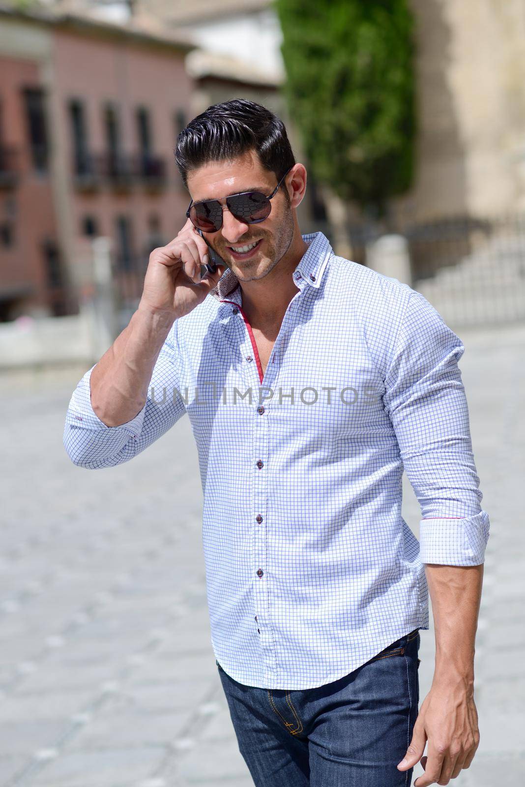 Portrait of good looking man in urban background talking on phone