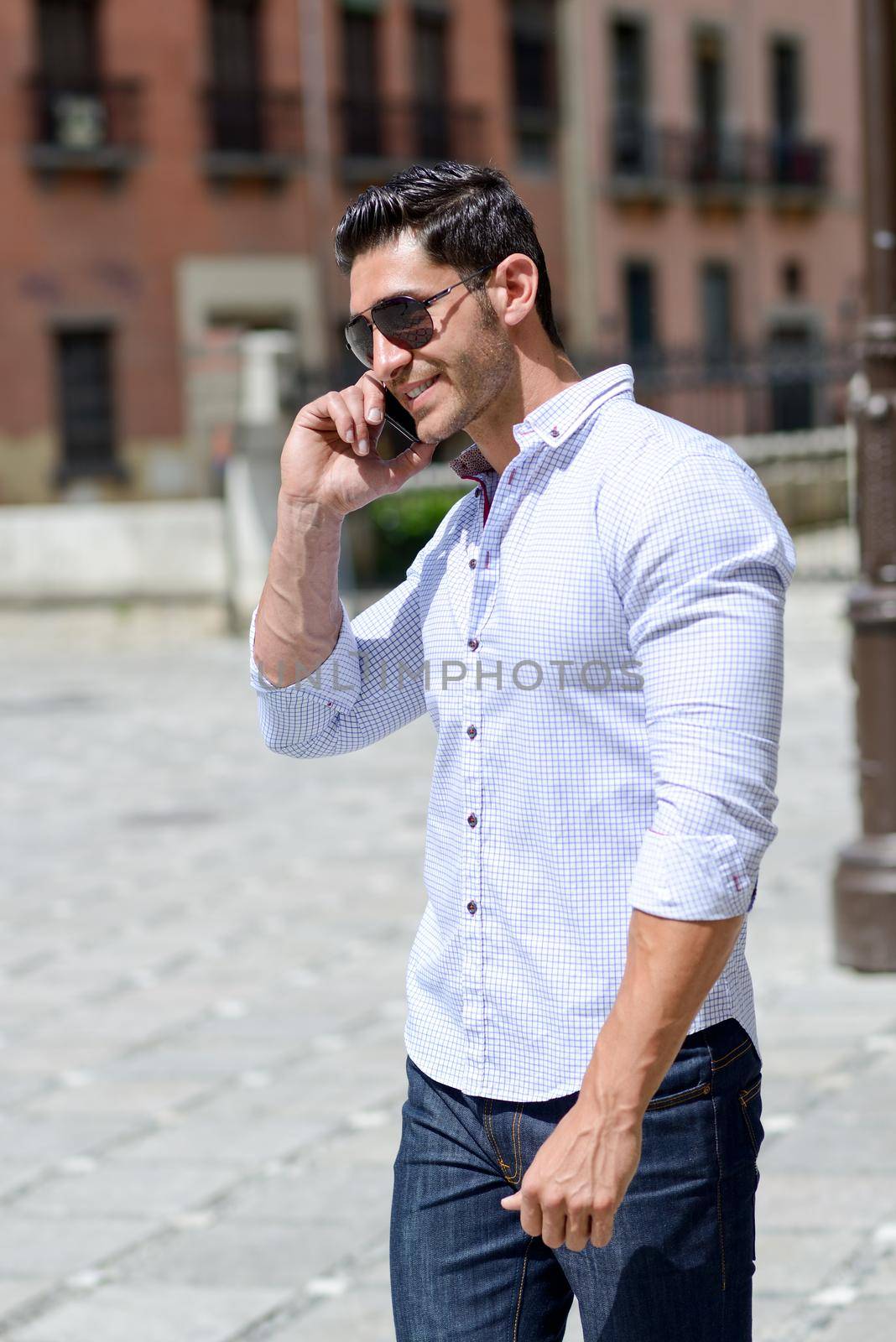 Handsome man in urban background talking on phone by javiindy