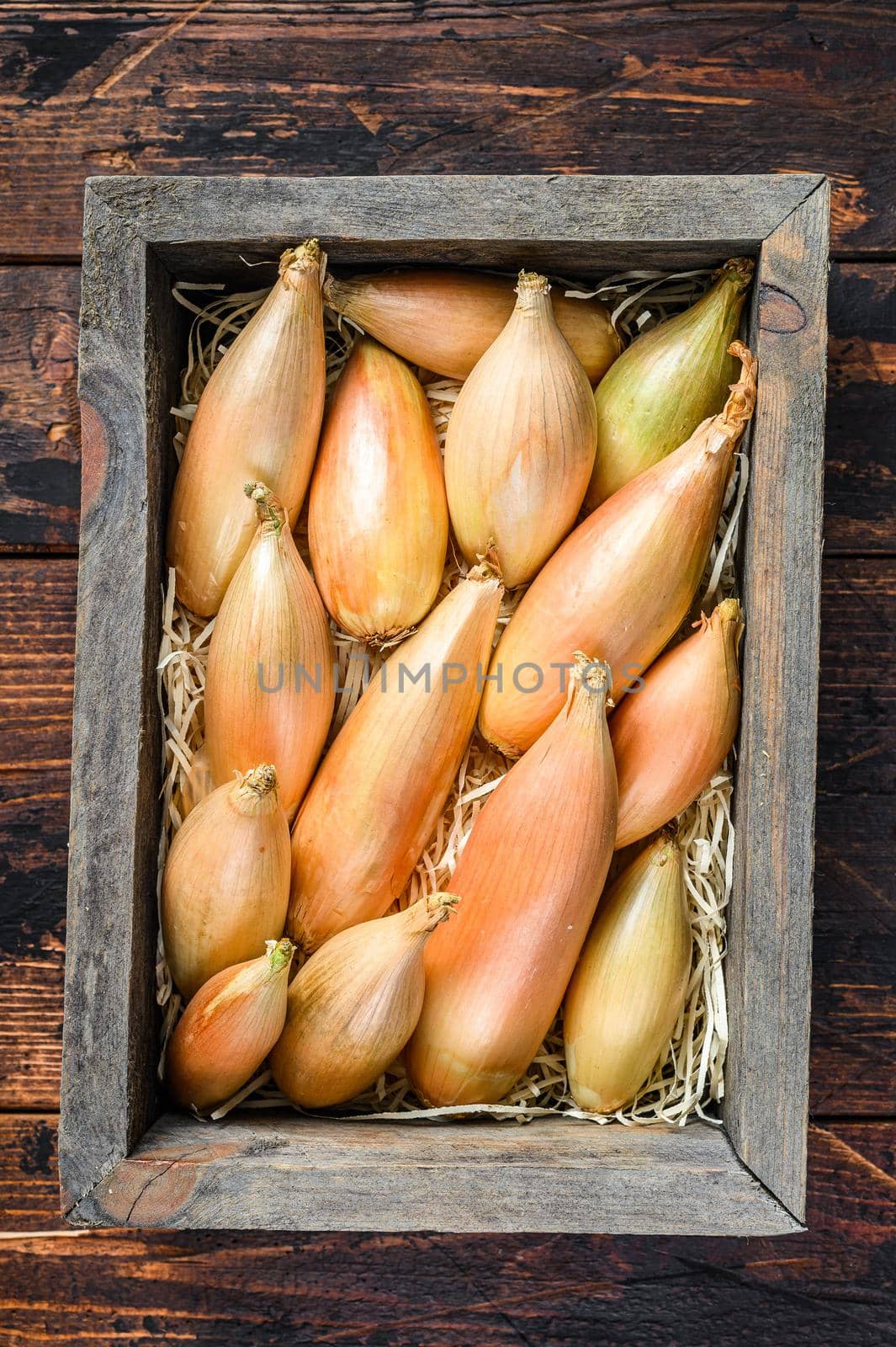 Raw Fresh Shallot onions Bulbs in a wooden market box. Dark Wooden background. Top view.