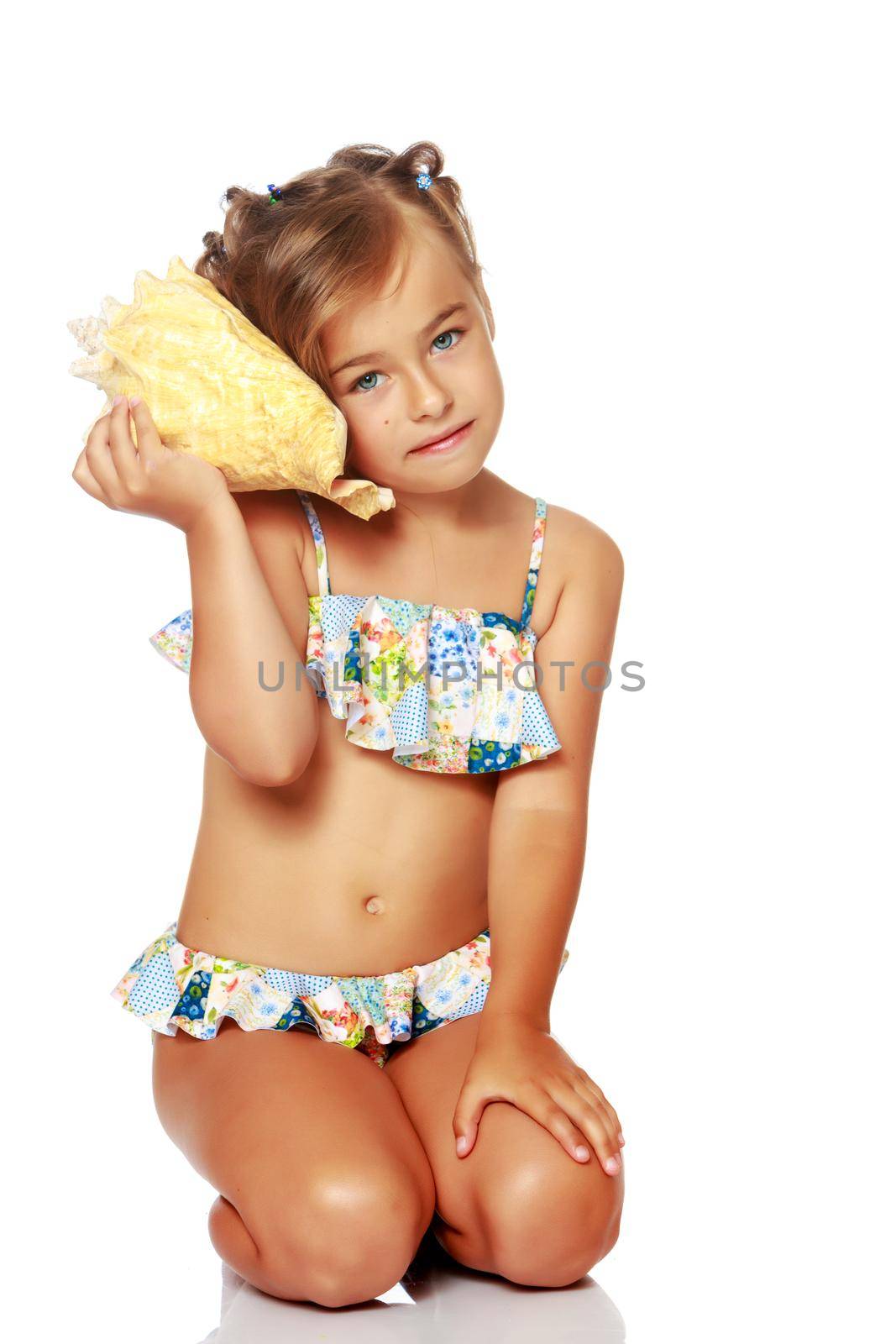 A little girl in a swimsuit with a shell. The concept of a family vacation at sea, a happy childhood. Isolated on white background.