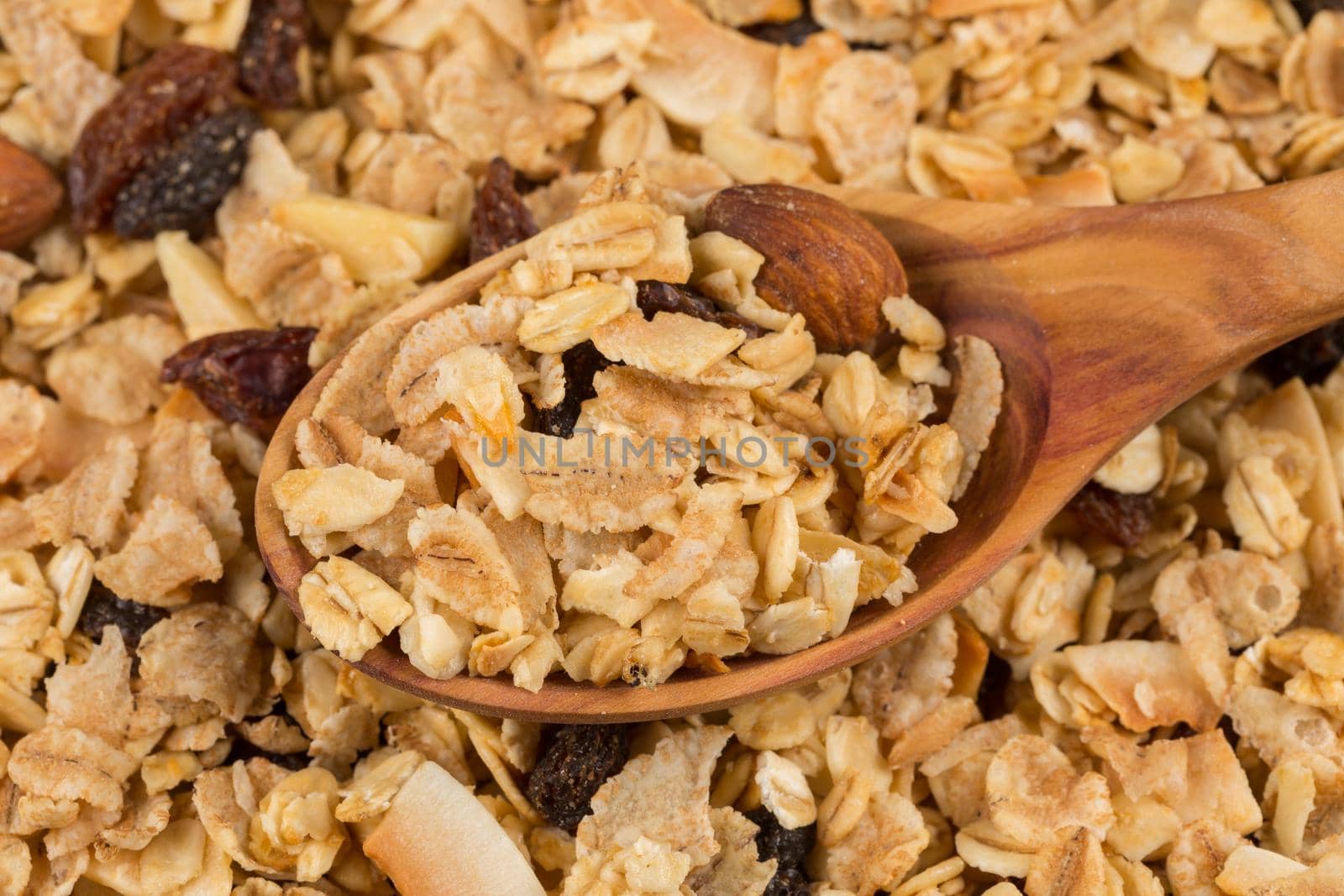 Top close view of a dry mix of fruit and almon nuts cereal and spoon