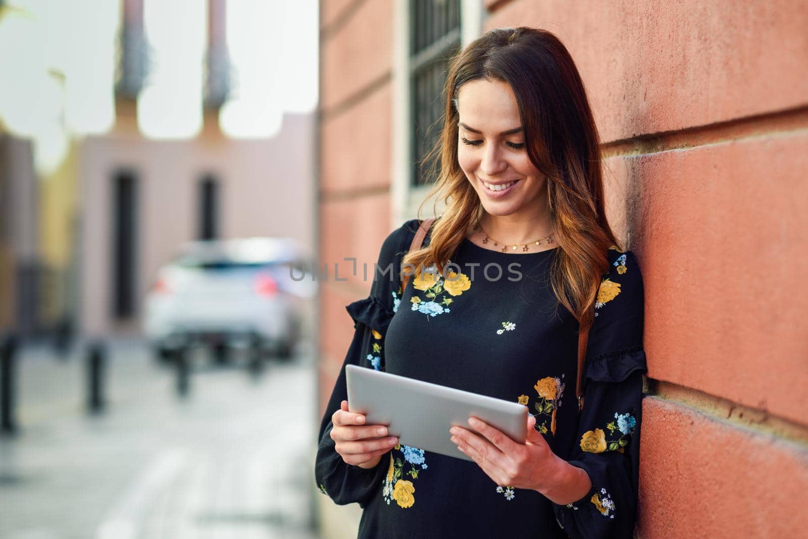 Young woman using digital tablet outdoors. Female in casual clothes with care hair in Granada, Andalusia, Spain.