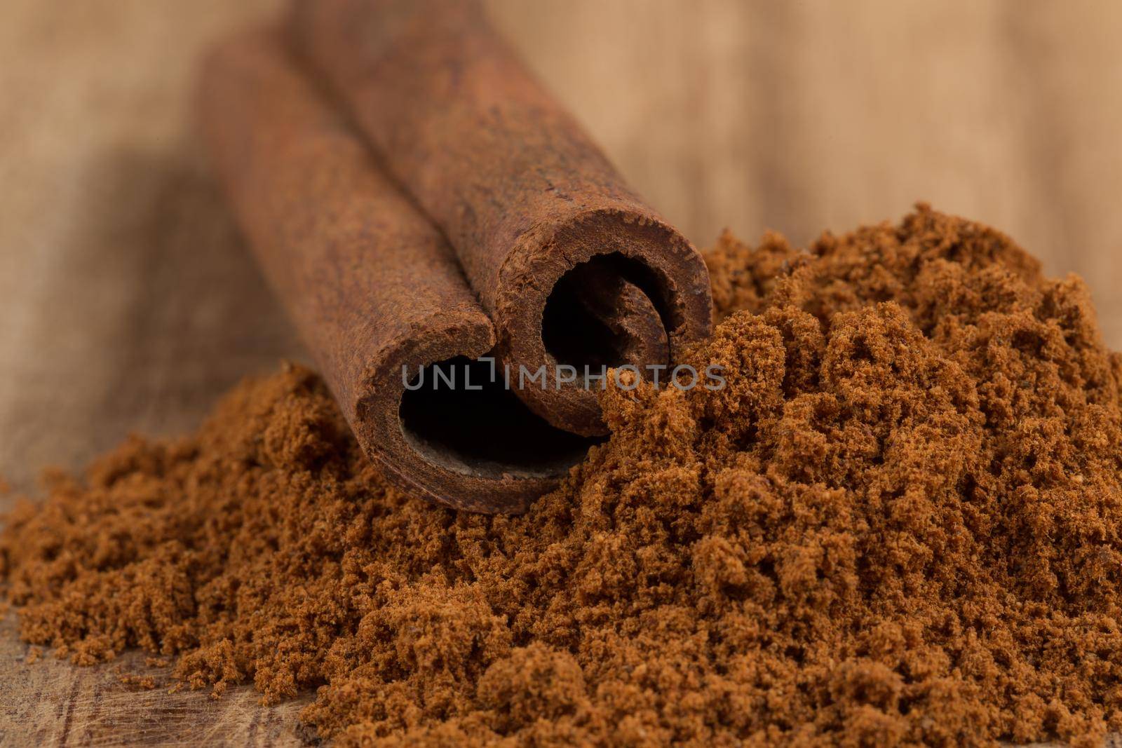 Cinnamon sticks with cinnamon powder on wooden background