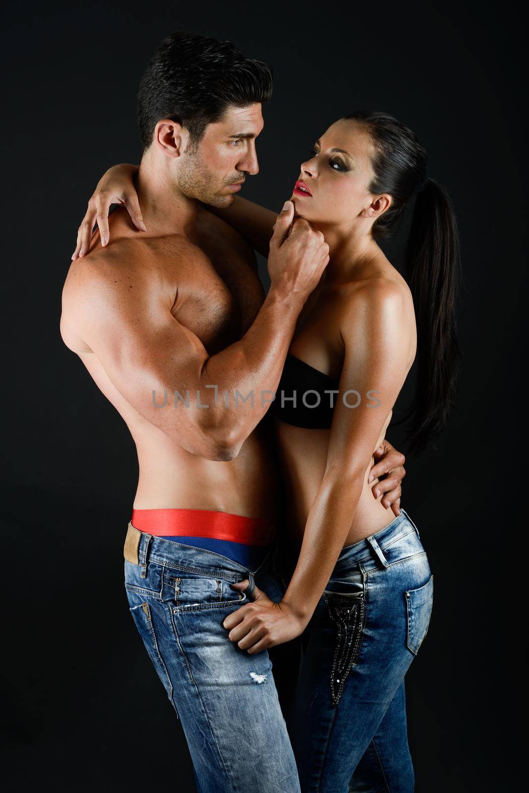 Sexy young couple with blue jeans standing together, studio shot