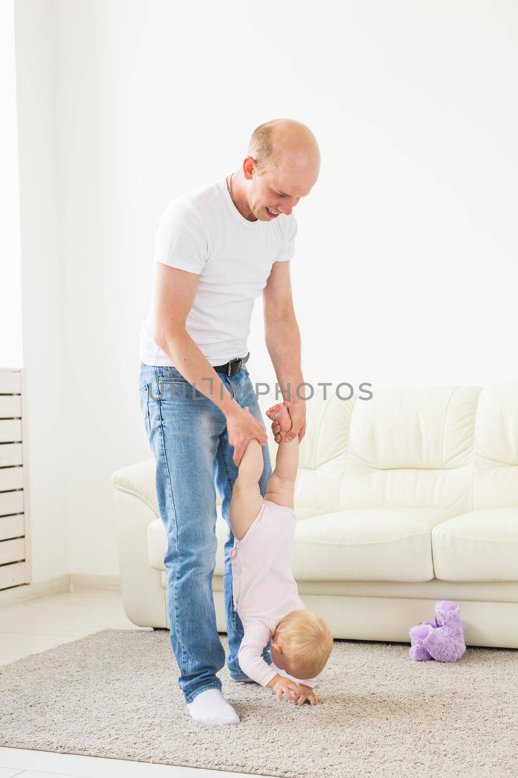 Fatherhood and family concept - Father and small toddler baby indoors at home, playing