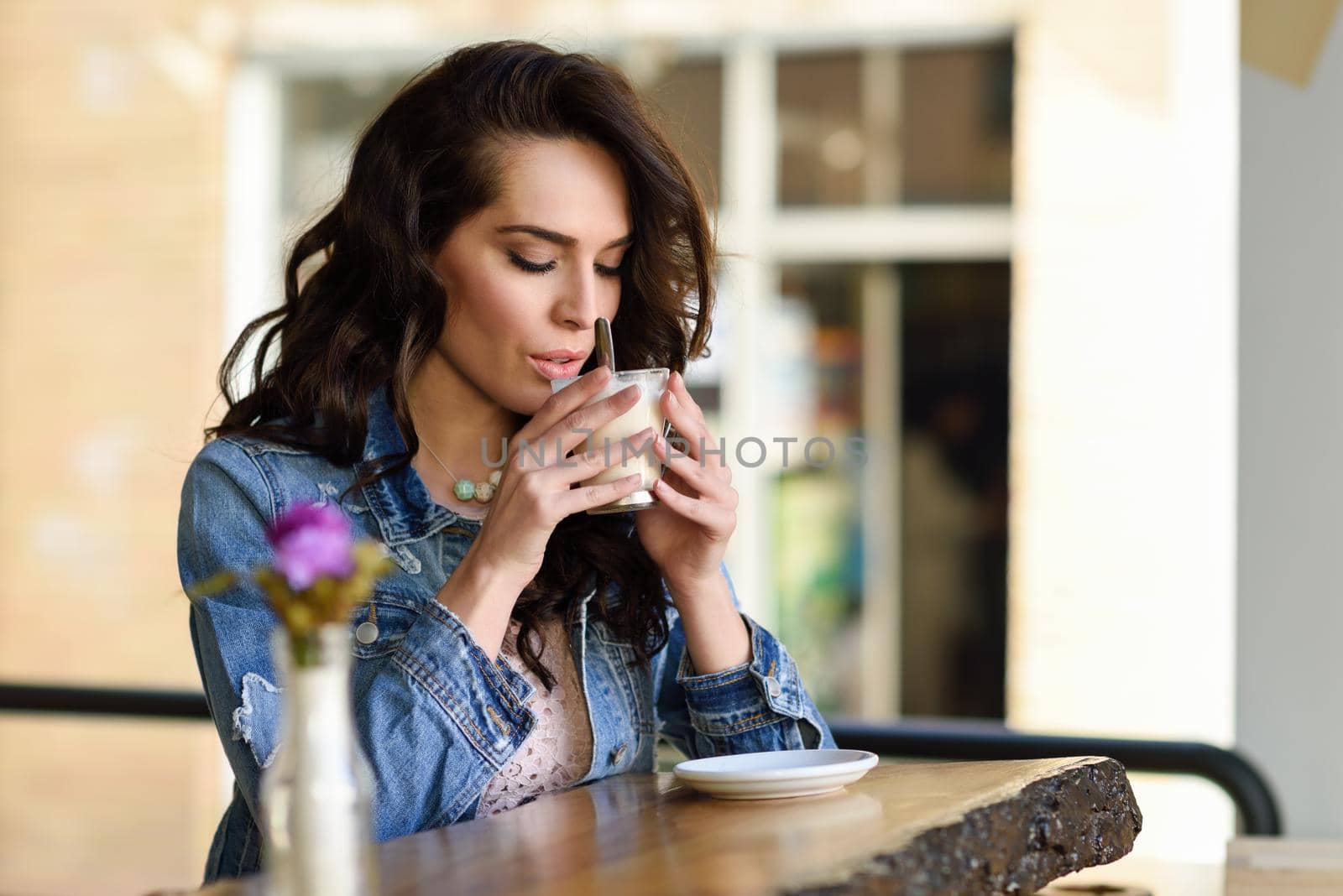 Young woman sitting indoor drinking coffee. Cool young modern caucasian female in her 20s. Cafe city lifestyle.