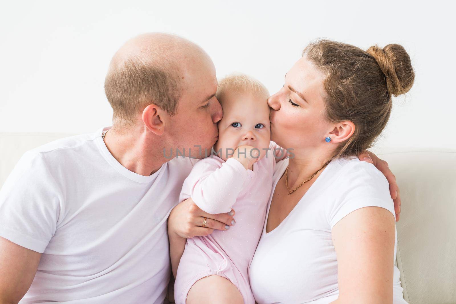 Happy family concept. Parents kissing baby smiling. by Satura86