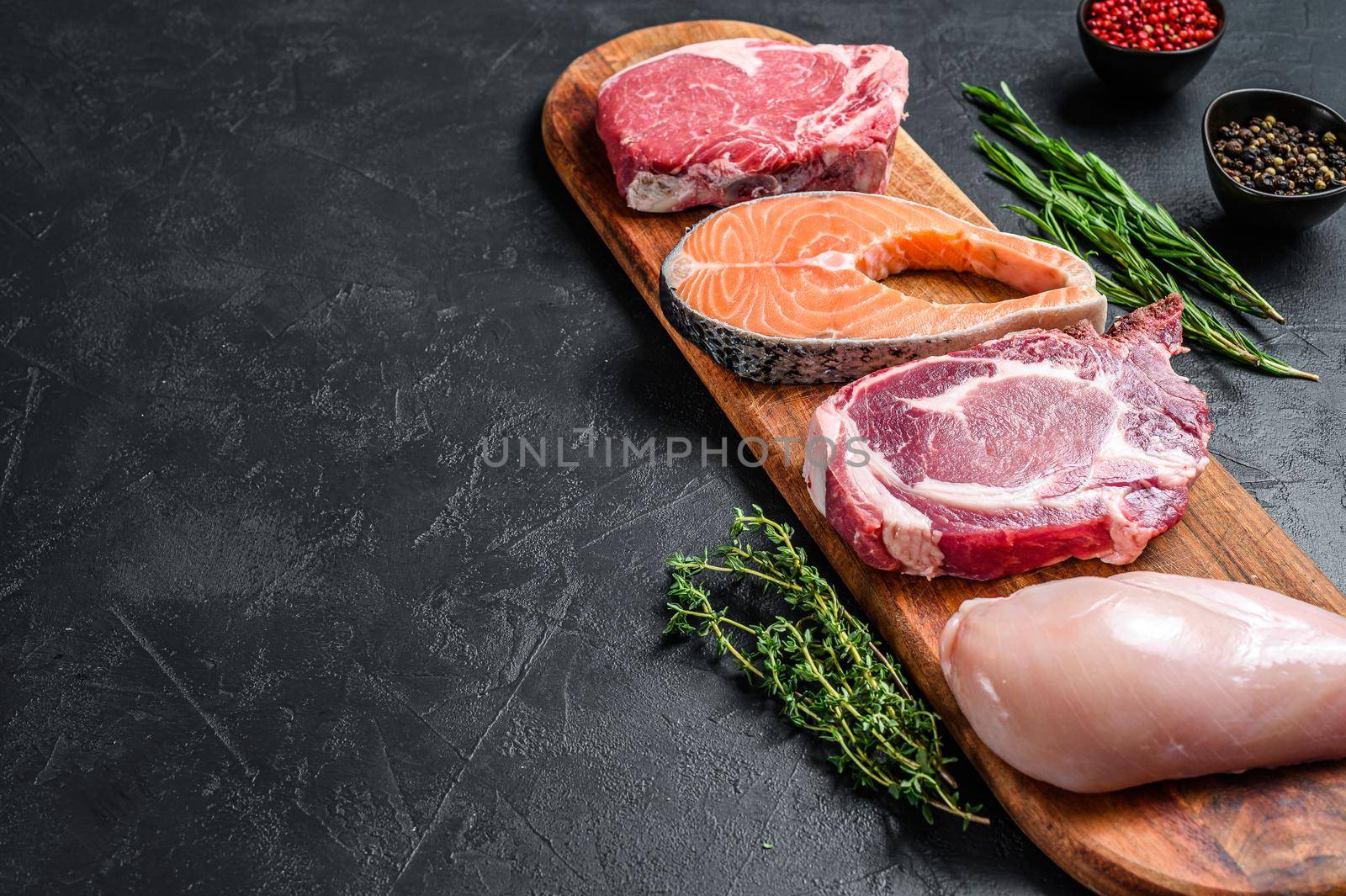 Mix of meat raw steaks salmon, beef, pork and chicken. Black background. Top view. Copy space.