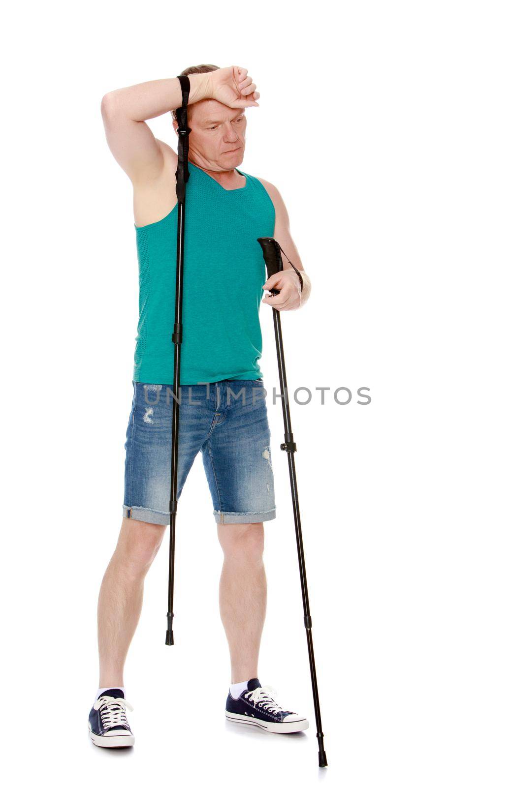 Man in t-shirt and shorts, Nordic walking sticks, hand wipes his sweat from his forehead -Isolated on white background