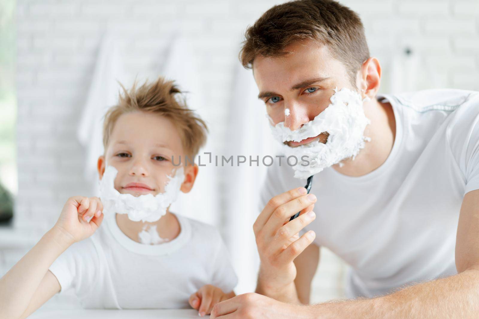 Father and his little son shaving together in bathroom